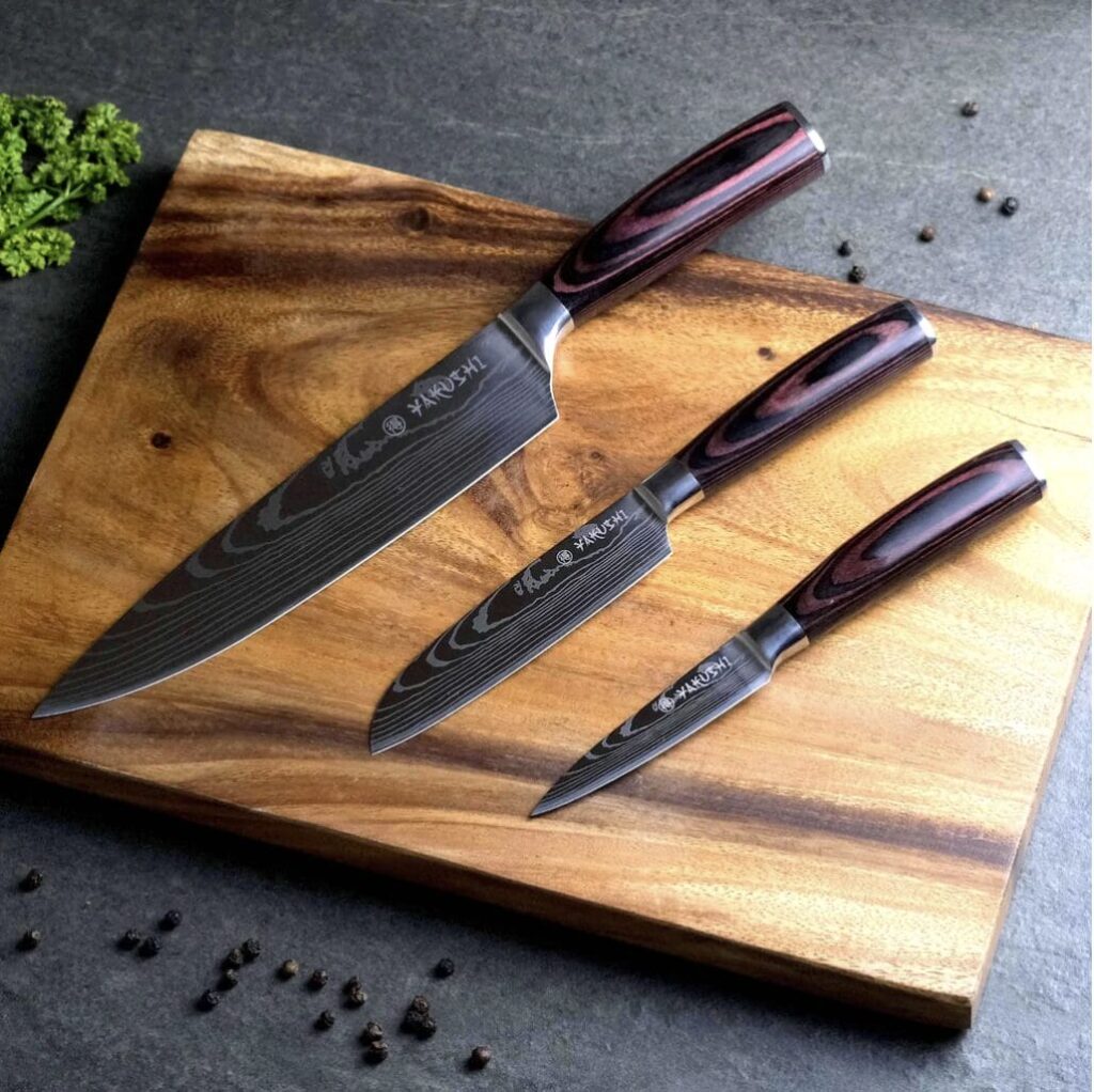 Damascus Kitchen Knife Set of Three knives on a wooden cutting board.