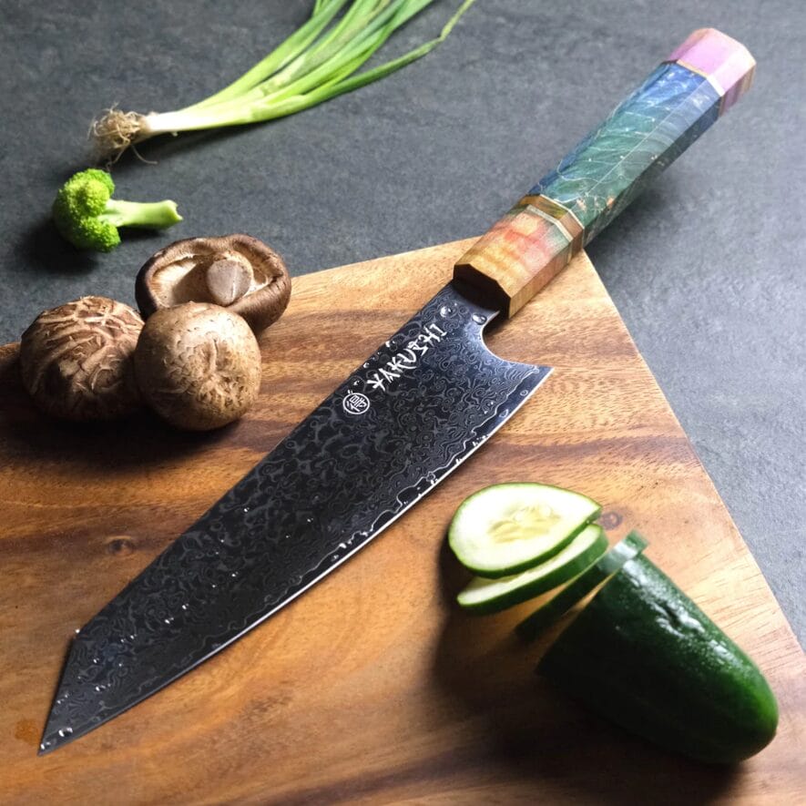 A kitchen knife on a cutting board with vegetables on it.