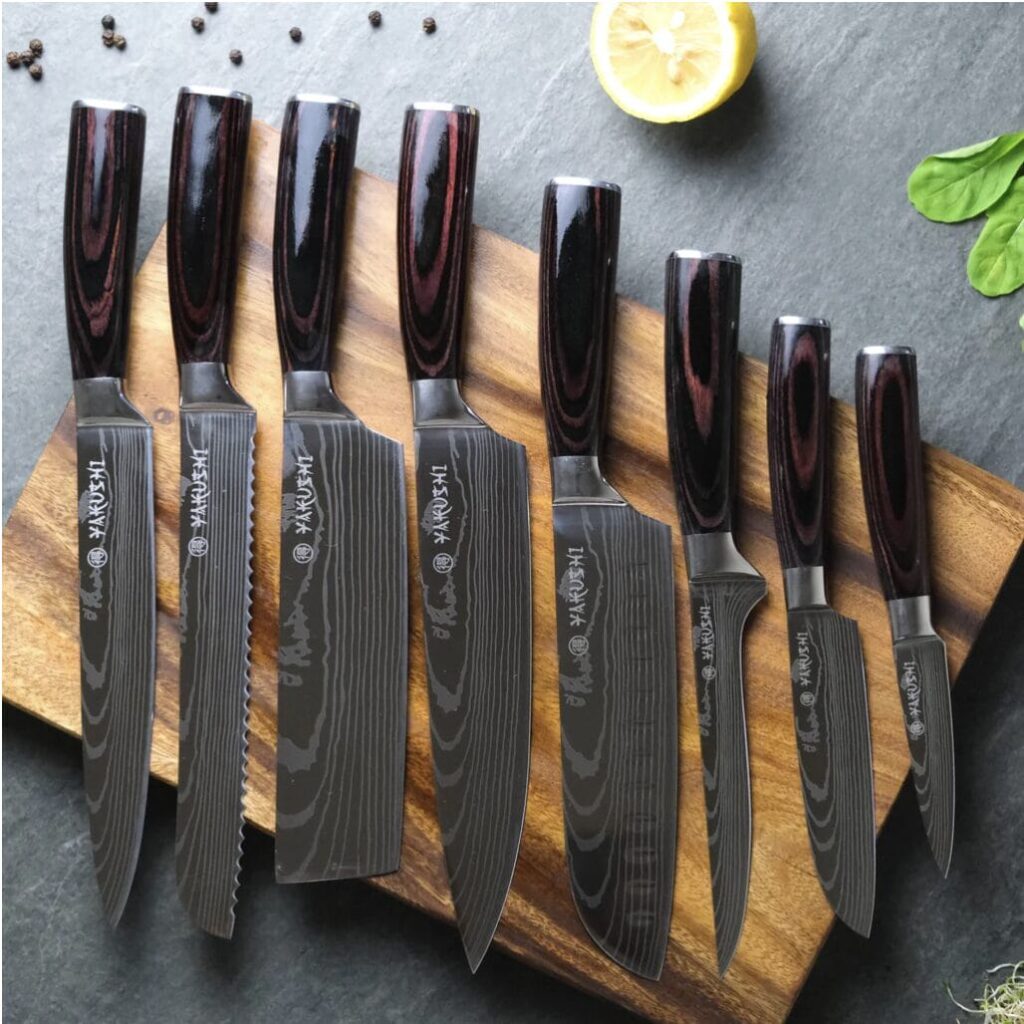 A set of Damascus kitchen knives on a cutting board.